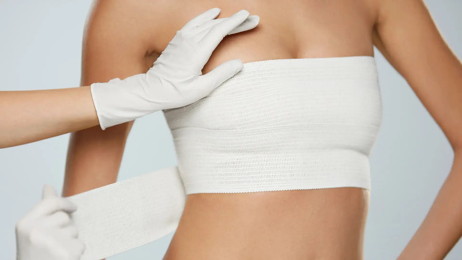 Plastic-Surgery.-Doctor-Hands-Wrapping-Female-Breast-In-Bandage